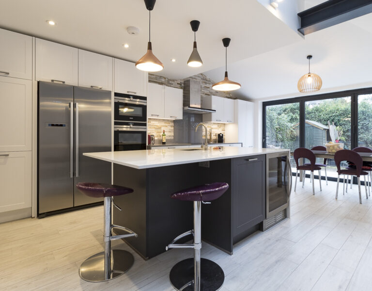 Luxury open-plan kitchen with island, pendant lighting, integrated appliances and dining area in a modern West London home