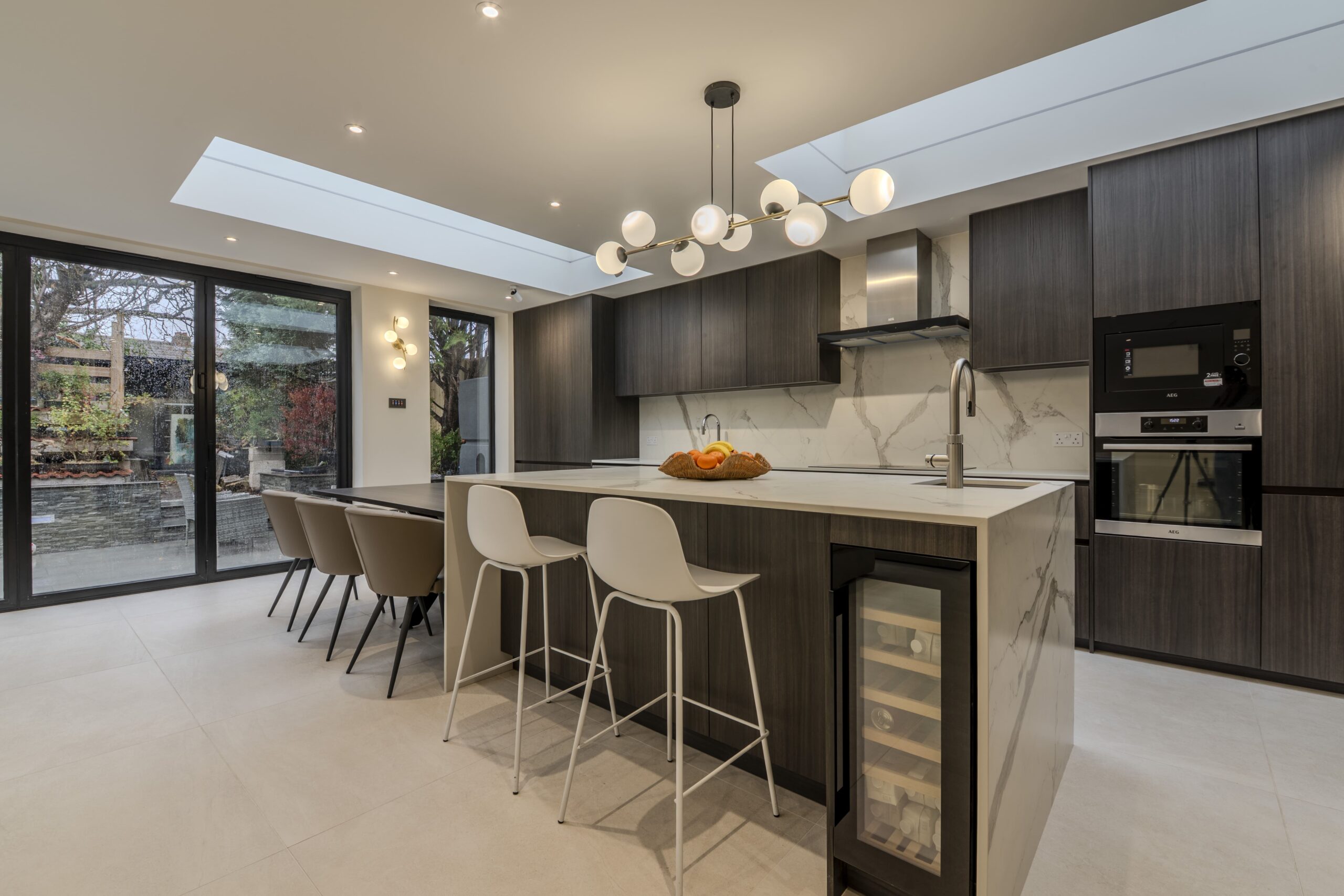Luxury modern kitchen with dark wood cabinetry, large island, skylight and open-plan layout in West London home