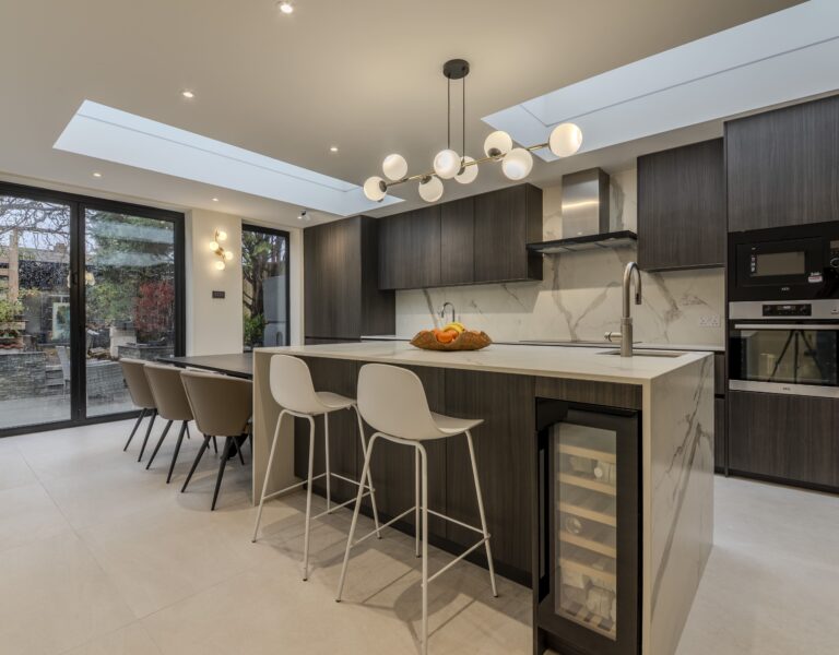 Luxury modern kitchen with dark wood cabinetry, large island, skylight and open-plan layout in West London home
